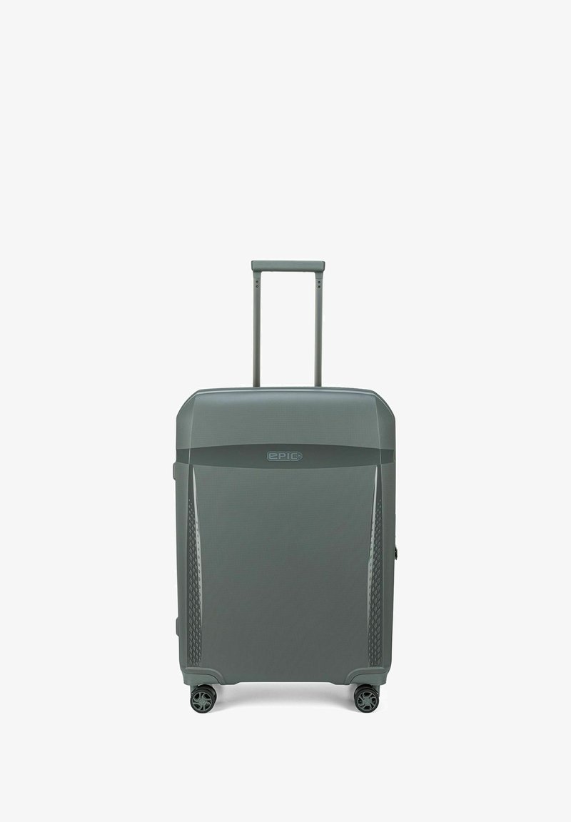 Maleta rígida gris con un patrón texturizado, mango retráctil y cuatro ruedas giratorias para mayor movilidad. Presenta un logotipo en la parte frontal.