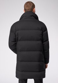 Cappotto imbottito nero con colletto alto, realizzato in tessuto liscio. Presenta sezioni cucite orizzontalmente e un taglio di lunghezza media, design senza cuciture.