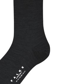 Svart strumpa gjord av mjukt material, med en jämn textur och en vit varumärkeslogotyp längs sidan. Enkelt, funktionellt design.