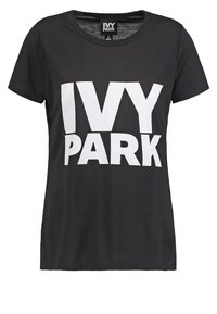 Camiseta de algodón negra con escote redondo y mangas cortas, que presenta un gran texto blanco que dice "IVY PARK" en la parte frontal.