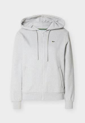 Hellgrauer Kapuzenpullover mit Reißverschluss, vorderen Taschen, Kordelzugkapuze, gerippten Bündchen und Saum sowie kleinem grünen Krokodil-Logo auf der linken Brust.