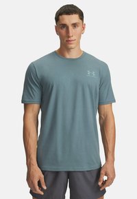 Šviesiai mėlynas sportinis marškinėlis, pagamintas iš minkšto medvilnės mišinio, su trumpomis rankovėmis ir apvaliu kaklu. Maža logo ant krūtinės.