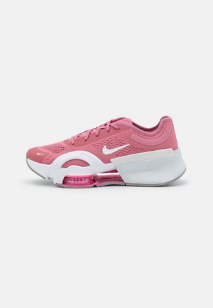 Zapatilla de running Nike rosa con parte superior de malla transpirable, entresuela blanca, unidad Air Zoom visible y suela texturizada sobre un fondo liso.