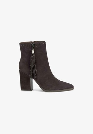 Botas de tobillo de ante gris con punta afilada, tacón ancho, cremallera lateral y detalle decorativo de borlas con tachuelas plateadas en la parte superior.