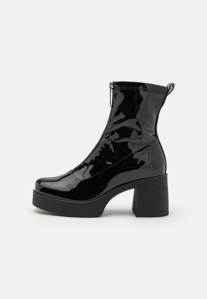 Botine negre din piele lacuită, cu toc bloc înalt, închidere cu fermoar și textură netedă. Dispune de un toc plat pentru stabilitate.