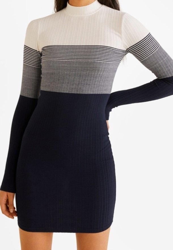 Femme portant une robe à manches longues côtelée avec des sections horizontales colorblock en blanc, rayé noir, gris et bleu marine.