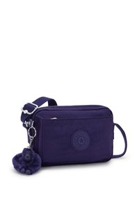 Ciemnoniebieska prostokątna torebka na ramię z regulowanym paskiem, przednia kieszeń na zamek, okrągłe logo Kipling oraz dołączony pluszowy breloczek w kształcie małpki.
