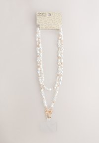 Double-strand white pearl and gold bead lanyard with gold clasps holding a clear ID badge holder.