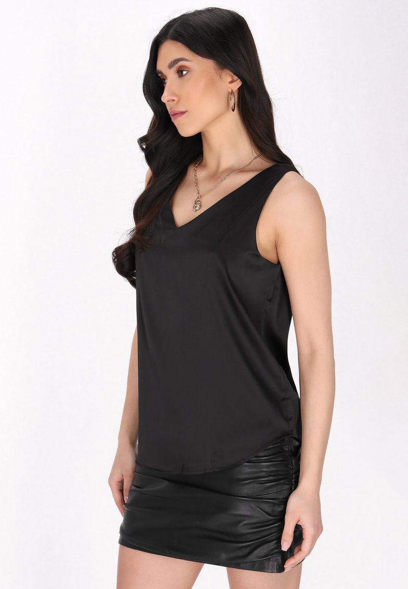 Top negru, fără mâneci, cu decolteu în V, realizat dintr-un material neted. Țesătura se așterne elegant, fiind completată de o fustă ajustată, plisată, din piele ecologică neagră.
