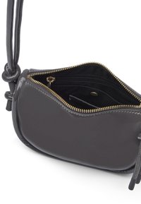 Borsa a mano in pelle verniciata nera con una texture liscia, forma curvilinea e chiusura con zip dorata. Presenta un dettaglio a nodo sulla tracolla.