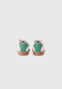 Baskets avec une tige en daim blanc, des accents de talon verts et une semelle en caoutchouc marron. Elles présentent un bout rond et un col rembourré pour le confort.