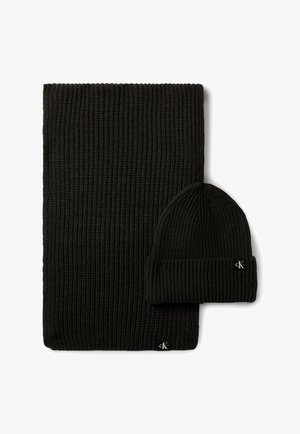 Czarny prążkowany dziany szalik i pasująca czapka typu beanie z podwiniętym mankietem, oba z małą metką z logo Calvin Klein.