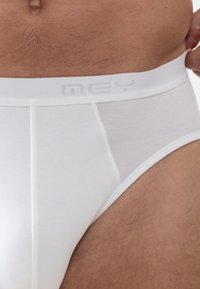 Hvide herreboxershorts med et gråt elastikbånd, lavet af glat bomuldsstof og med en tætsiddende pasform. Enkel design uden mønstre eller detaljer.