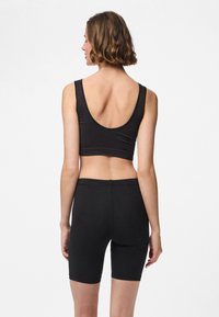 Melns ribots crop top ar plašu apaļu izgriezumu, kopā ar melnām augsta vidukļa velosipēdu šortiem, abi izgatavoti no mīksta, elastīga auduma.