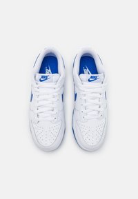 Weiße Nike-Sneaker mit blauen Akzenten, ausgestattet mit einer perforierten Zehenbox, flachen Schnürsenkeln und einer gepolsterten Innensohle. Klassisches Low-Top-Design.