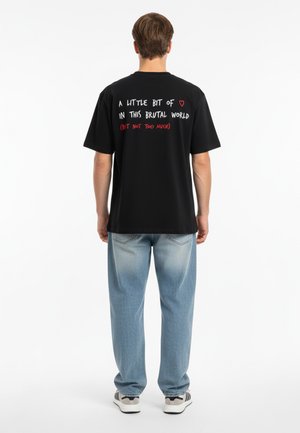 Zwarte katoenen t-shirt met korte mouwen, voorzien van kleurrijke tekst op de achterkant: "EEN BEETJE ❤️ IN DEZE BRUTALE WERELD (MAAR NIET TE VEEL)."