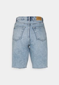 Ljusblå denimshorts med fransad fåll, med två bakfickor och en beige etikett i midjebandet. Texturerad, avslappnad design.