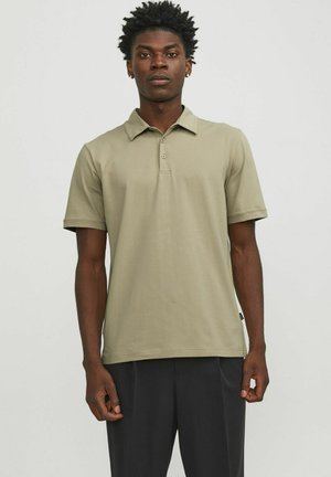 Olivengrøn polo t-shirt lavet af blødt stof, med krave, tre knapper og korte ærmer. Bæres med mørke bukser.