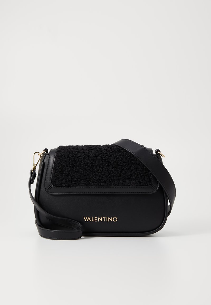 Black leather handbag with a textured black fur flap, gold branding, and an adjustable strap. Features a sleek, rounded silhouette.
