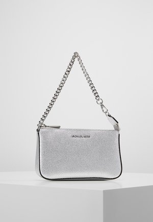 Petit sac à main argenté texturé avec bandoulière chaîne et fermeture éclair, posé sur un piédestal blanc contre un fond gris clair uni.