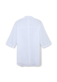 Camicia bianca ampia e svasata con maniche corte e larghe. Presenta una cucitura a yoke sul retro e un orlo dritto. Realizzata in tessuto leggero e morbido.