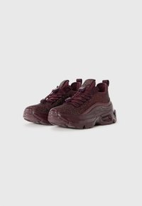 Chaussures de sport bourgogne avec un dessus en maille texturée, design à lacets et semelle épaisse et rembourrée. Les caractéristiques incluent une languette de traction et des accents réfléchissants.