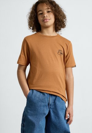 Bruine crewneck t-shirt, korteborduim, van zachte katoen, met een klein zwart logo op de borst, gecombineerd met losse blauwe denim shorts.
