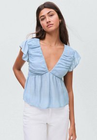 Light blue blouse with a deep V-neck, gathered frill sleeves, and a loose fit. The fabric appears soft and slightly textured.
