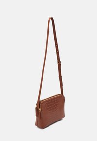 Hnědá crossbody taška z kůže s embosovaným krokodýlím vzorem, se zipovým uzávěrem, nastavitelným popruhem a hladkým povrchem. Akcenty v zlatém tónu.