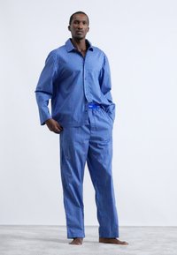 Pijama albastră și albă cu carouri, formată dintr-o cămașă cu nasturi și mâneci lungi, împreună cu pantaloni largi, confecționată dintr-un material moale.