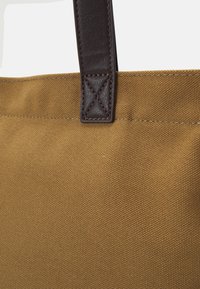 Leinen-Tote-Bag in warmem Braun mit strukturierter Oberfläche. Ledergriff mit gesticktem Akzent. Robustes Design, das für den täglichen Gebrauch geeignet ist.