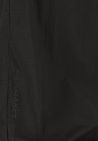 Schwarze Jacke aus strukturiertem Stoff mit einem dezenten Karomuster. "ENDURANCE"-Logo an der Seite sichtbar. Leichtes und stromlinienförmiges Design.