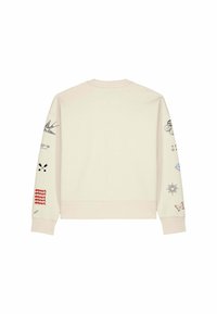Sweat-shirt beige à manches longues avec plusieurs petits tatouages graphiques noirs et rouges imprimés le long des deux manches.