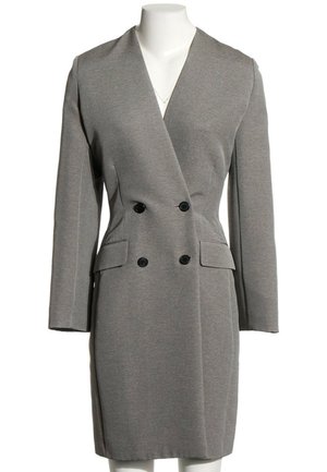 Vestido blazer gris de doble botonadura con mangas largas, botones negros y dos bolsillos con solapa delante, sobre un maniquí blanco.