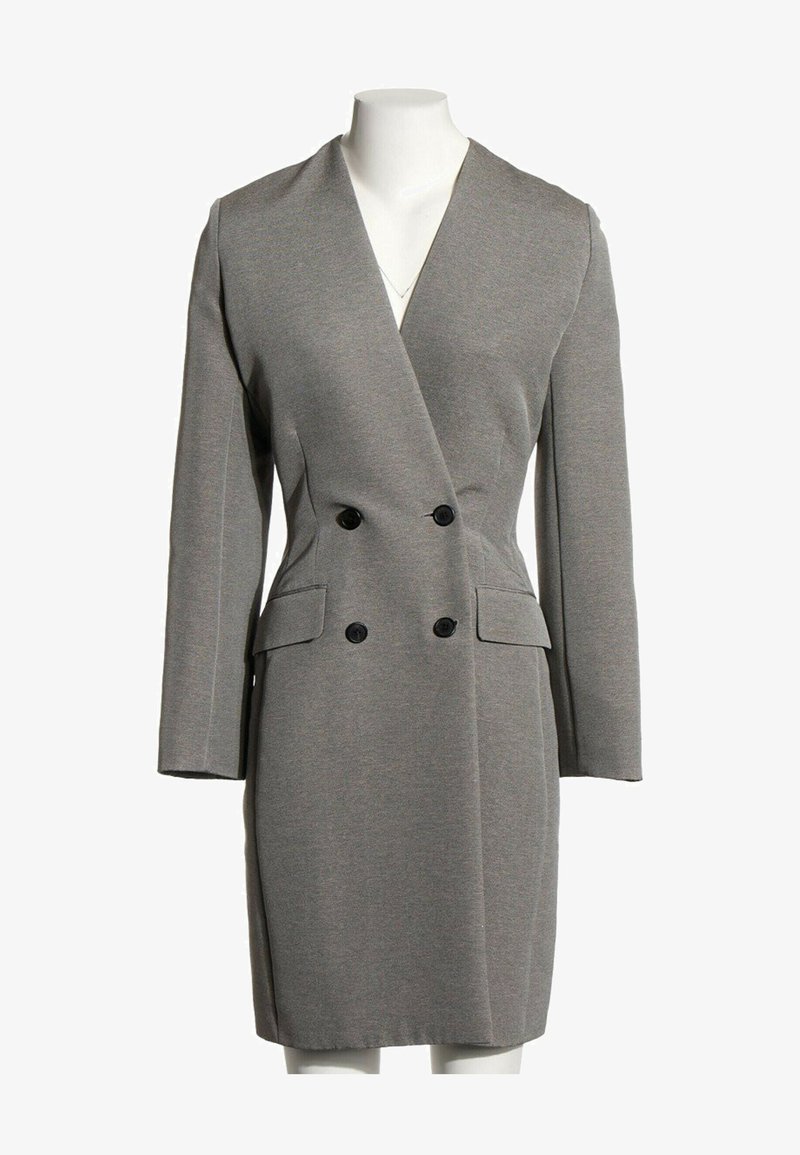 Robe blazer grise à manches longues, double boutonnage, boutons noirs et deux poches à rabat à l'avant, sur un mannequin blanc.