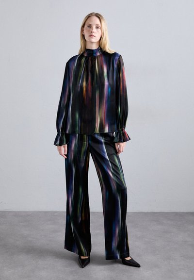 Set di blusa di seta e pantaloni a gamba larga con un vivace motivo a righe multicolore su sfondo nero. Maniche a volant e scollatura alta.