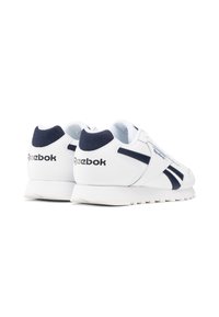 Baskets Reebok blanches avec des accents et un logo bleu marine, vues de l'arrière et sur le côté sur un fond blanc.