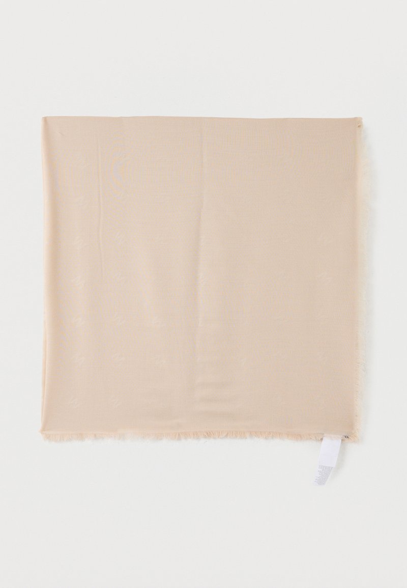 Μπεζ τετράγωνο μαντίλι με διακριτικό υφαντό μοτίβο και κρόσσια στα άκρα, απλωμένο επίπεδα με εμφανή λευκή ετικέτα φροντίδας σε λευκό φόντο.