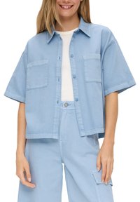 Light blue denim short-sleeve shirt with a button front, two chest pockets, and a relaxed fit. Smooth texture, casual design.