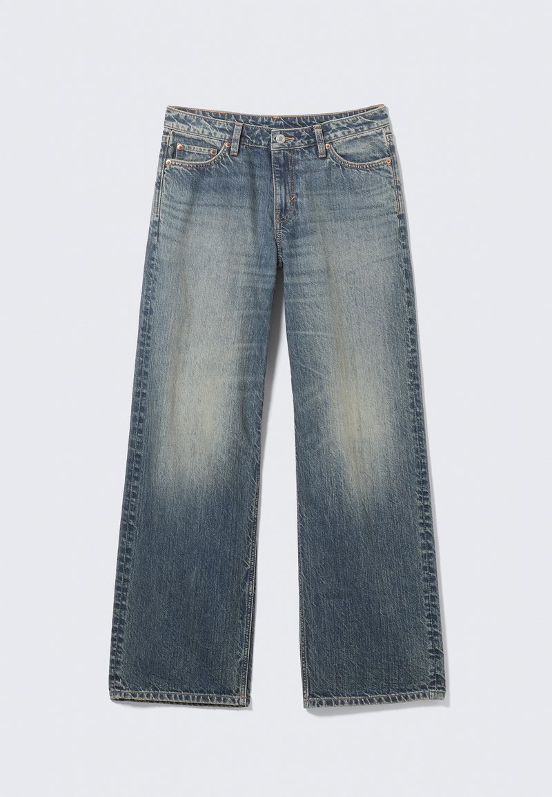 Jean large bleu clair en denim. Zones délavées sur les cuisses et les genoux. Taille standard avec cinq poches et accents métalliques.