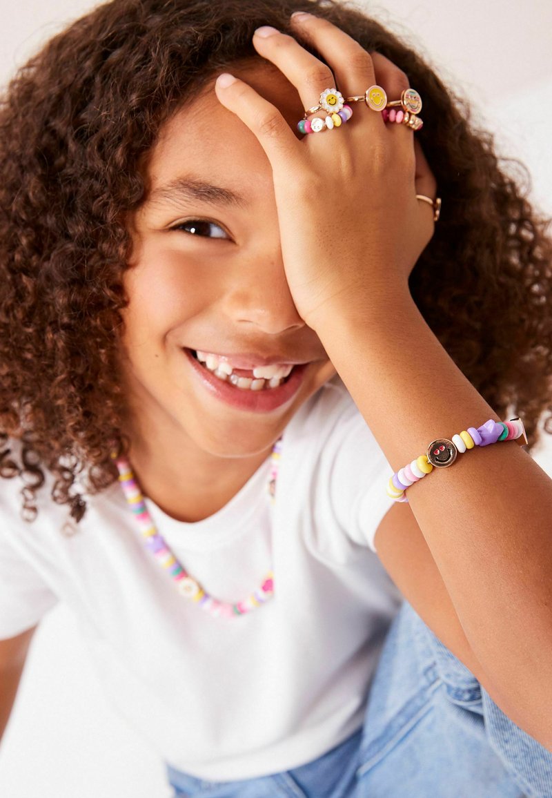 Bunte Perlen-Schmuckset mit einem Smiley-Gesicht-Charm, das verschiedene Pastellfarben zeigt. Aus Kunststoff gefertigt und lässig getragen.