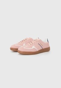 Adidași din suede roz cu accente albe, cu sistem de încălțare cu șireturi și talpă din cauciuc brun. Prezintă un detaliu mic bleumarin la călcâi și logo.