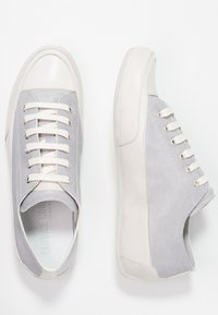 Šedé a krémové tenisky z kůže a semiše, s kulatou špičkou, zvýšeným podpatkem a klasickým šněrovacím designem s kovovými očky.