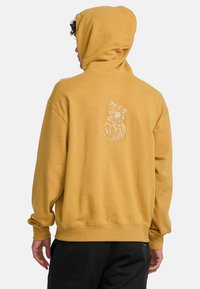 Yellow hoodie made from soft fabric, featuring a kangaroo pocket, ribbed cuffs, and a patterned logo on the back.