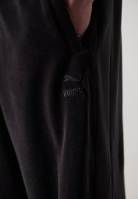 Sorte fleece joggers med et slankt design, sidelommer og et diskret broderet Puma-logo på venstre lår. Blød tekstur.