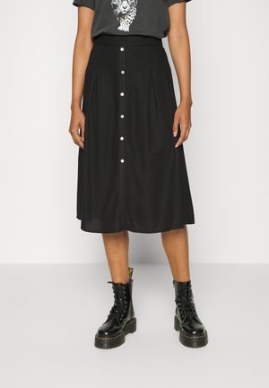 Sort midi-nederdel med knapper foran, båret med sorte snørebånds kampstøvler og en t-shirt med leopardprint grafik.