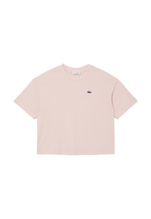 Camiseta corta de color rosa claro con mangas cortas y un pequeño logo de cocodrilo bordado en el lado izquierdo del pecho.