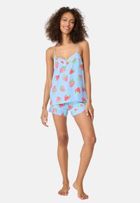 Light blue pajama set with spaghetti straps; features vibrant red strawberry prints; shorts have a similar pattern; soft fabric texture.