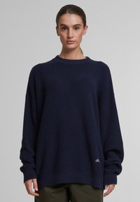 Maglione lavorato a maglia blu navy con texture a costine, design oversized, maniche larghe e un piccolo logo ricamato all'orlo.