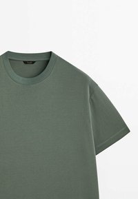 T-shirt à manches courtes fabriqué en tissu olive vert doux et léger. Il présente un col rond et une coupe décontractée avec un design uni.